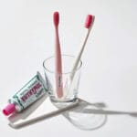 Brosse à dents Euthymol Whitening - Brosse à dents manuelle blanche avec technologie Flex-Firm pour une élimination en douceur de la plaque dentaire. Illustration brosses à dents dans un pot avec dentifrice. 